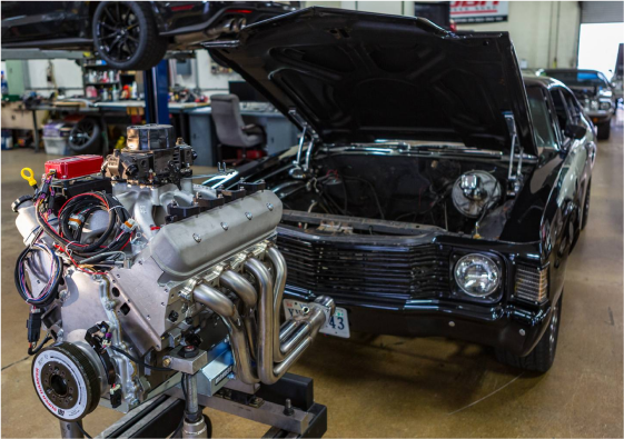 An engine sitting on a rack in front of an open hood
