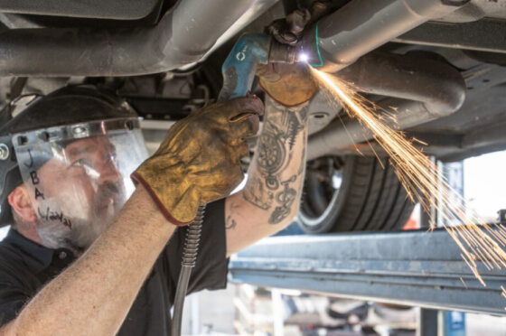 A JBA technician working on the underside of a car