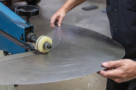A JBA technician cutting out a piece of metal for custom fabrication