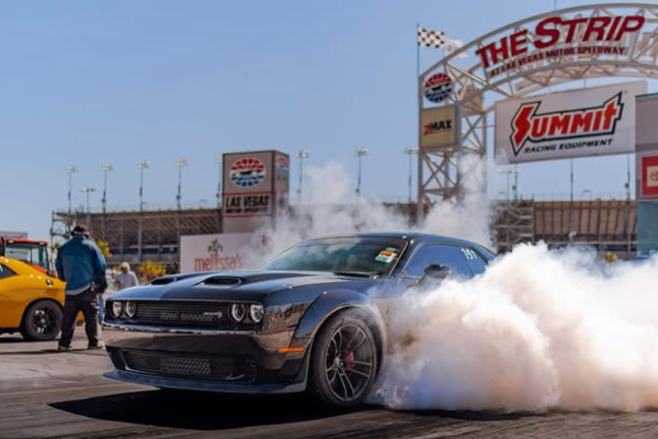 A muscle car doing a burnout in front of The Strip sign